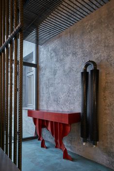 a red bench sitting in the middle of a room next to a tall metal object