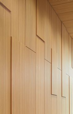 an empty bench in front of a wall with wooden slats on it's sides