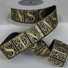 two rolls of black and gold decorative ribbon on a white surface with an ornate design