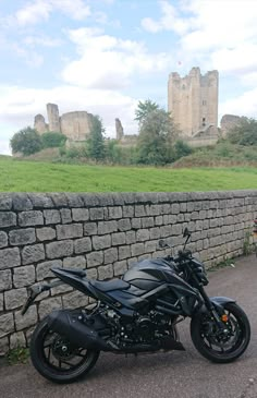 a black motorcycle parked next to a stone wall