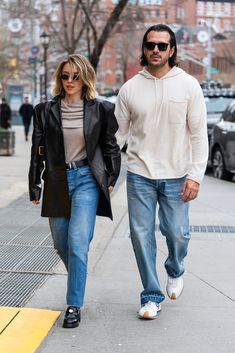 a man and woman are walking down the street together, one is wearing a black jacket