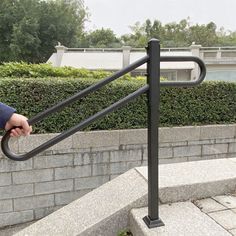 a man is walking up some stairs with his hand on the handlebars and he is wearing a blue jacket