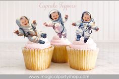 three cupcake toppers with two babies in space suits and one is falling off the cake