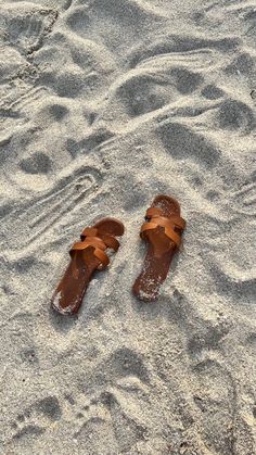 a pair of brown sandals sitting on top of a sandy beach