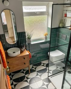 a bathroom with black and white tile flooring and green tiles on the shower wall