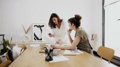 two women sitting at a table with papers