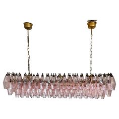 a long chandelier with pink glass bottles hanging from it's sides and two brass fittings on each end