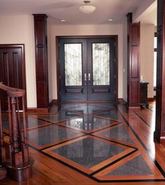 an empty room with wooden doors and marble flooring in the center, surrounded by wood columns