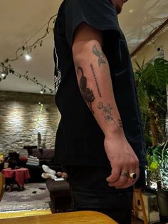 a man with a tattoo on his arm standing next to a table