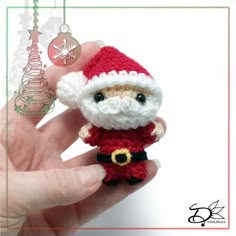 a hand holding a small crocheted santa clause ornament in it's palm