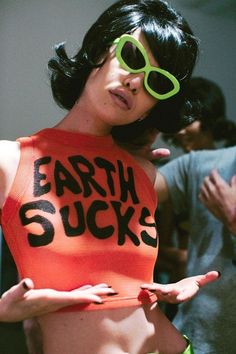 a woman with green goggles on her head and an orange shirt that says earth sucks