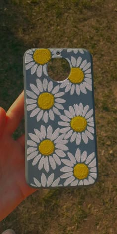 a hand holding up a cell phone case with daisies on it