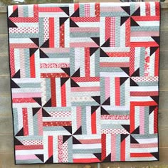 a red, white and black quilt hanging on a wall