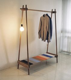 an empty room with a clothes rack, lamp and jacket on the hanger next to it