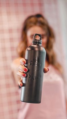 a woman holding a water bottle in front of her face