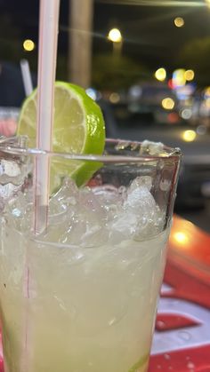 a close up of a drink with ice and lime on a table in a restaurant