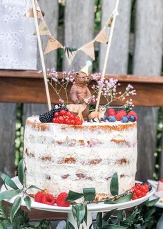 a cake decorated with berries, raspberries and bunting flags