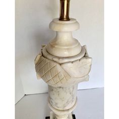 a white marble table lamp with a gold colored light bulb on it's base