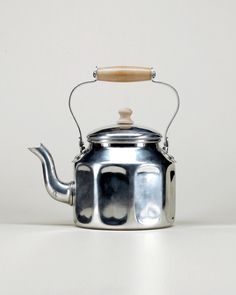 a silver tea kettle with a wooden handle