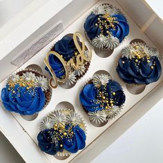 cupcakes with blue frosting and gold sprinkles in a box