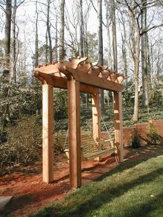 a wooden bench sitting in the middle of a forest next to a swing set and trees