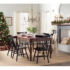 a dining room table with chairs and a christmas tree in front of the fire place