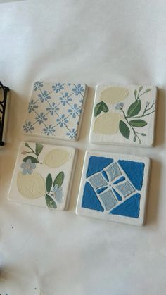 four coasters with flowers and leaves on them sitting on a table next to a sewing machine