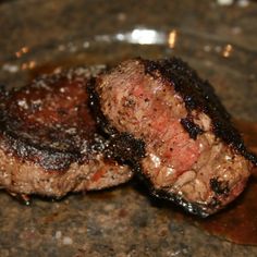 two pieces of steak sitting on top of a glass plate covered in sauce and ketchup