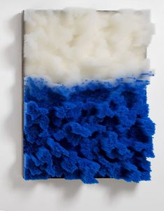 a blue and white piece of art hanging on a wall