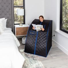 a woman sitting in a bed with a black and blue quilted cover on it