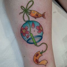 a colorful tattoo on the leg of a woman with fish and flower decorations around it