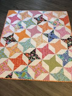 a multicolored quilt is laying on the floor