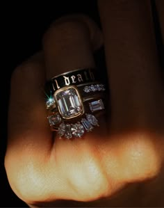 a person's hand holding a ring with diamonds and emeralds on it in the dark