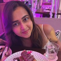 a woman sitting at a table in front of a plate with some food on it