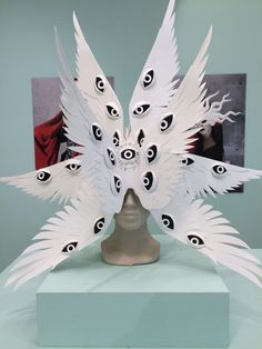 a white mask with feathers on top of it