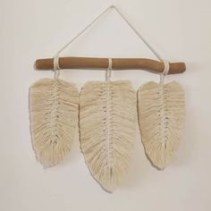 three pieces of woven hanging on a wall with a wooden stick in front of them