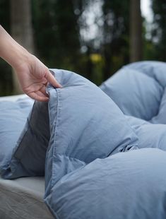 a person reaching for pillows on top of a bed