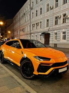 an orange sports car is parked on the side of the road in front of a building