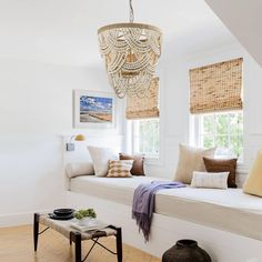 a living room filled with furniture and a chandelier hanging over the window seat