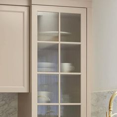 a kitchen with white cabinets and marble counter tops in front of a window that has glass doors