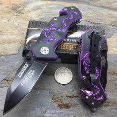 a purple and black knife sitting on top of a counter next to a dime coin