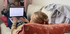 a woman sitting on a couch using a laptop computer