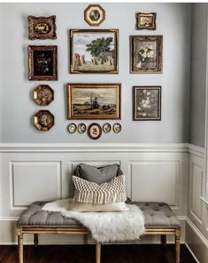 a bench in front of a wall with many pictures on it and a fur rug