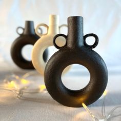 three black and white vases sitting on top of a table