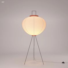 a floor lamp with a white shade on it and a black wire in the middle