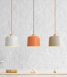 three pendant lights hanging over a white counter top with chopsticks on the side