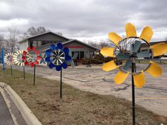 several colorful windmills on poles in front of a building