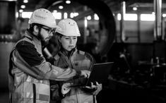 two people in hard hats are looking at something