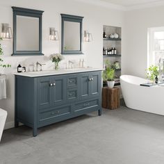 a white bath tub sitting next to two sinks in a bathroom under mirrors and lights