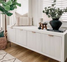 a living room with white furniture and plants on the window sill next to it